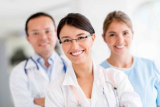 Smiling healthcare professionals in white coats looking at the camera.