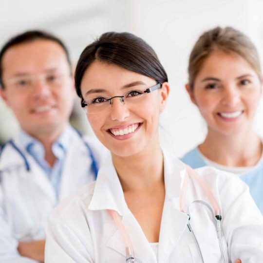 Smiling healthcare professionals in white coats looking at the camera.