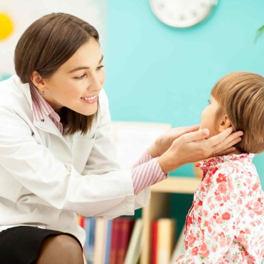 Doctor examining a young girl's throat in a clinic.