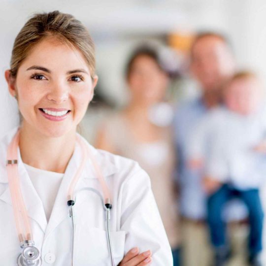 Smiling female doctor with stethoscope and family in background.
