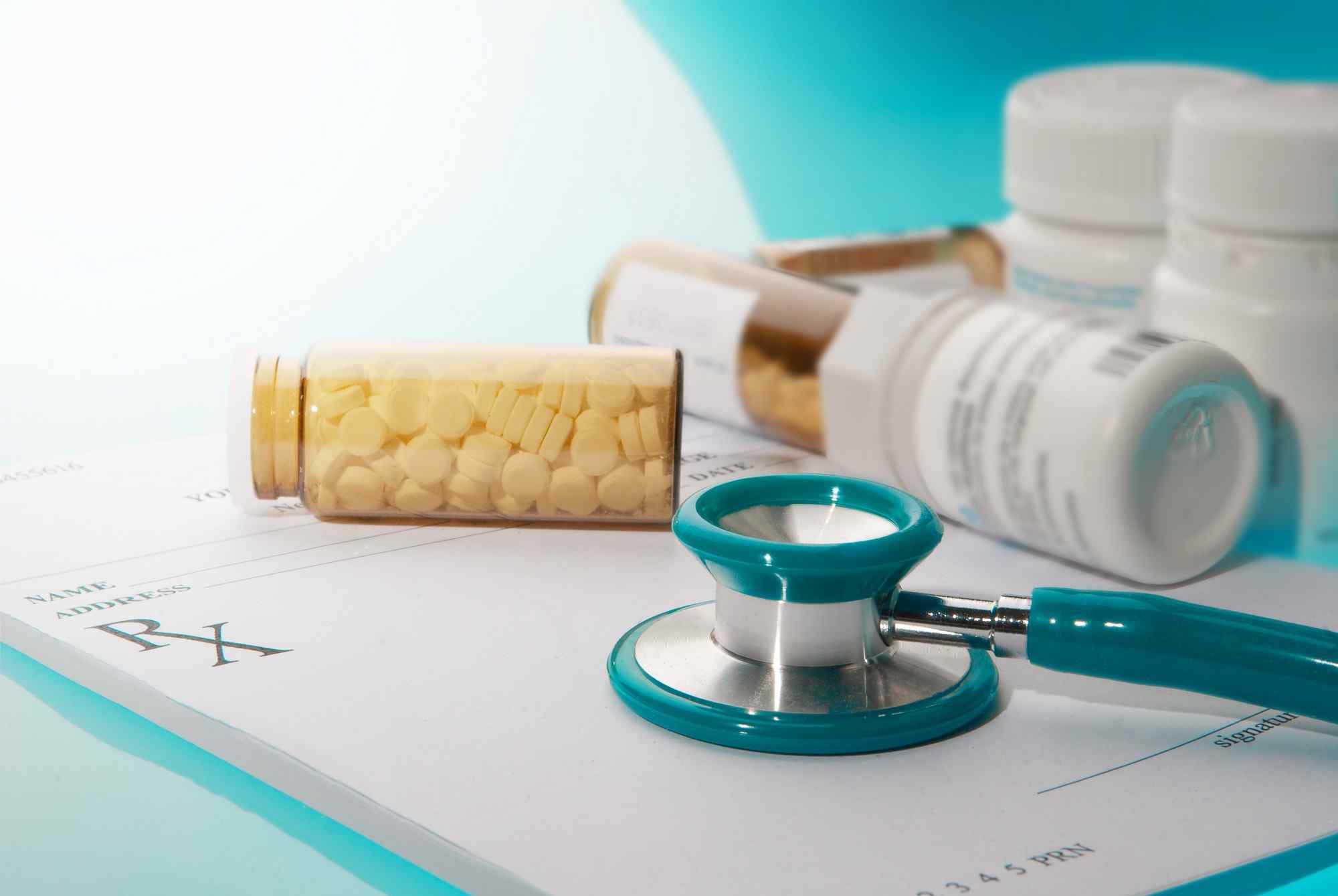 A stethoscope and prescription bottle on a white table.