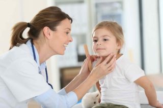 Doctor examining a young girl's throat during a check-up.