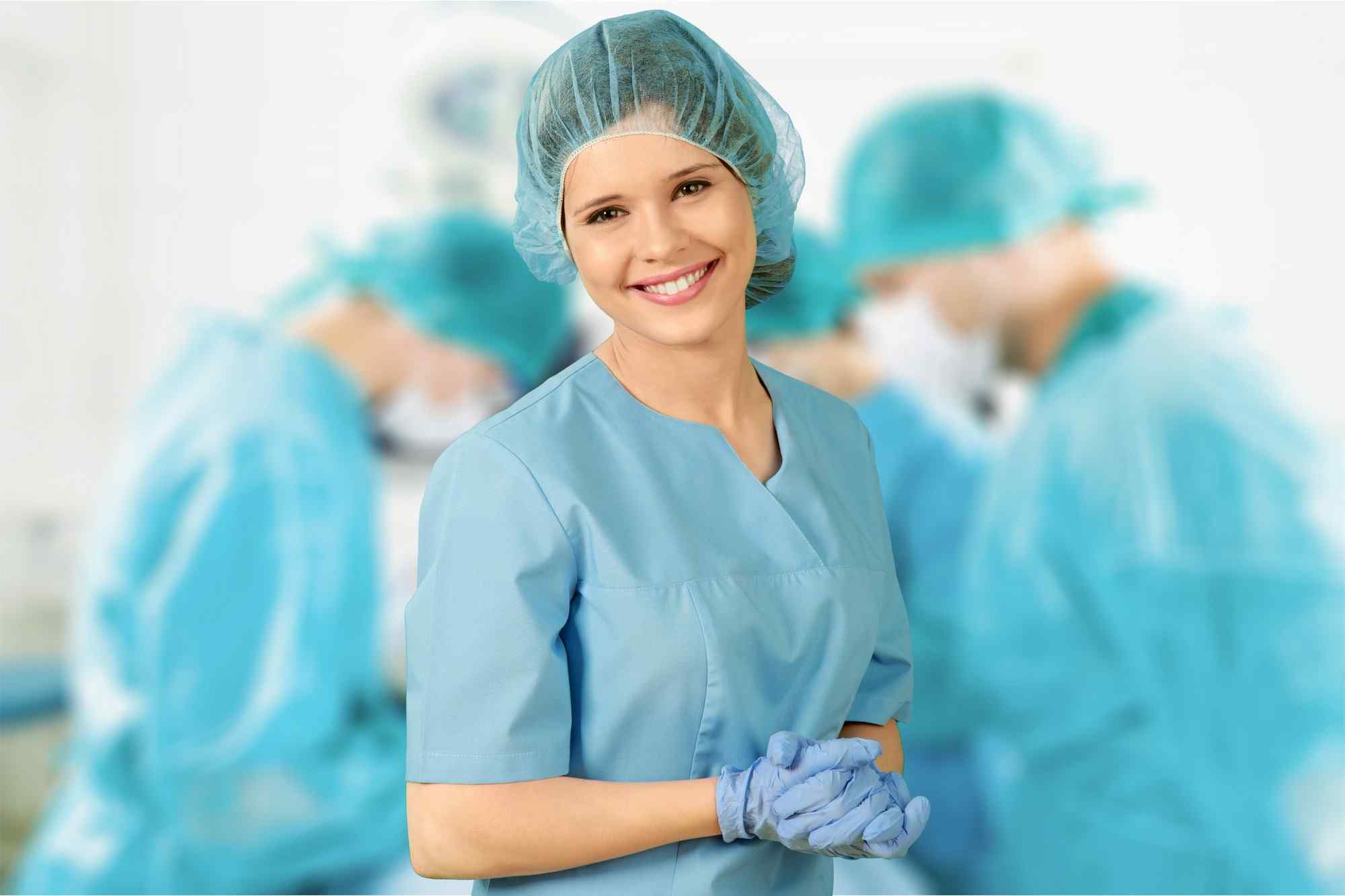 Smiling healthcare professional in scrubs and gloves.