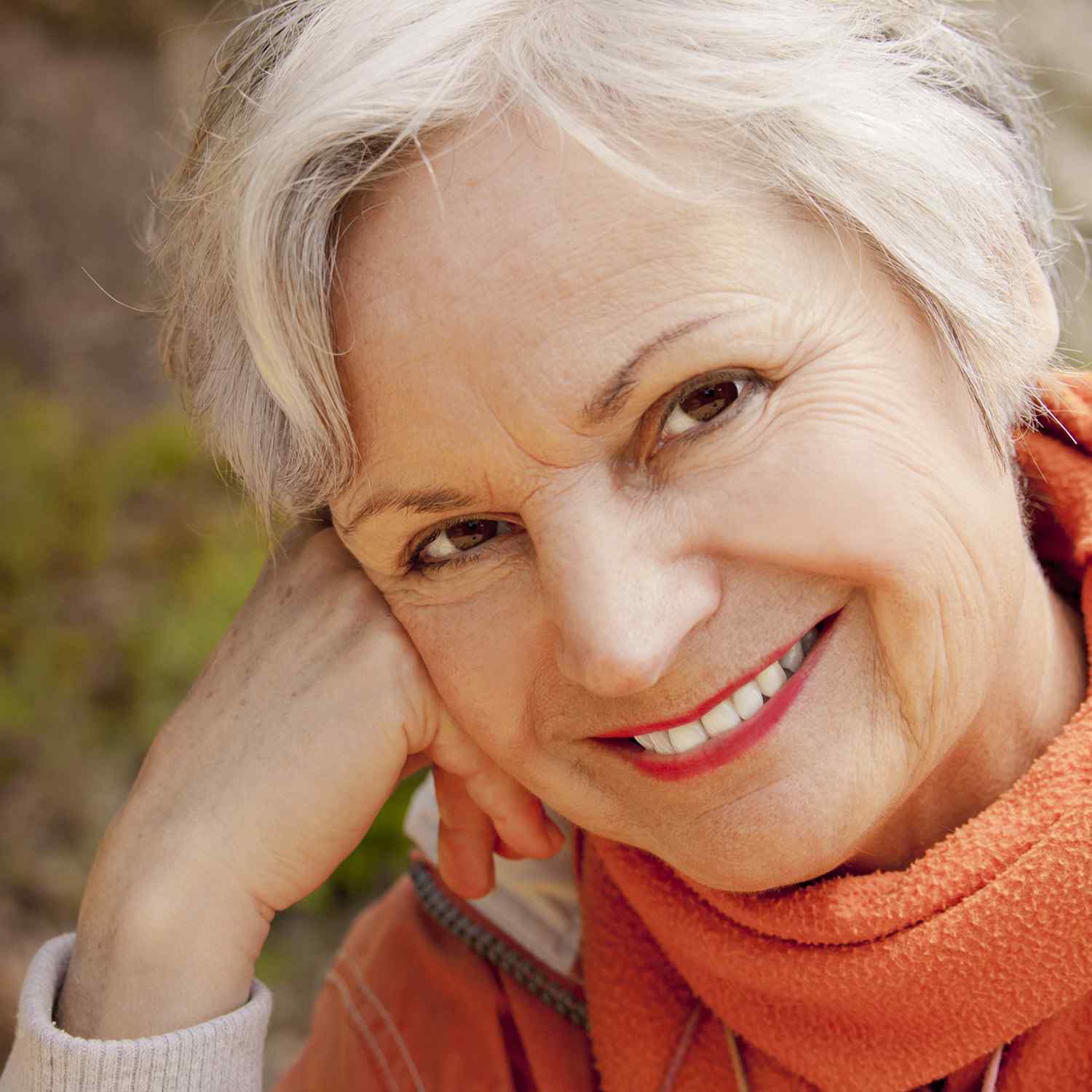 Smiling elderly woman with white hair and an orange scarf.