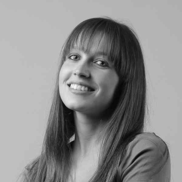 Smiling young woman with straight hair and bangs in black and white.