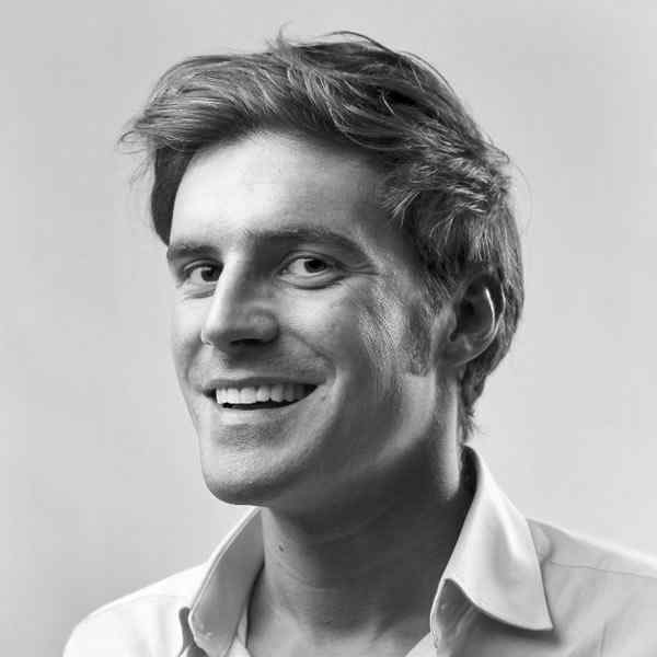 Black and white portrait of a smiling man with tousled hair.