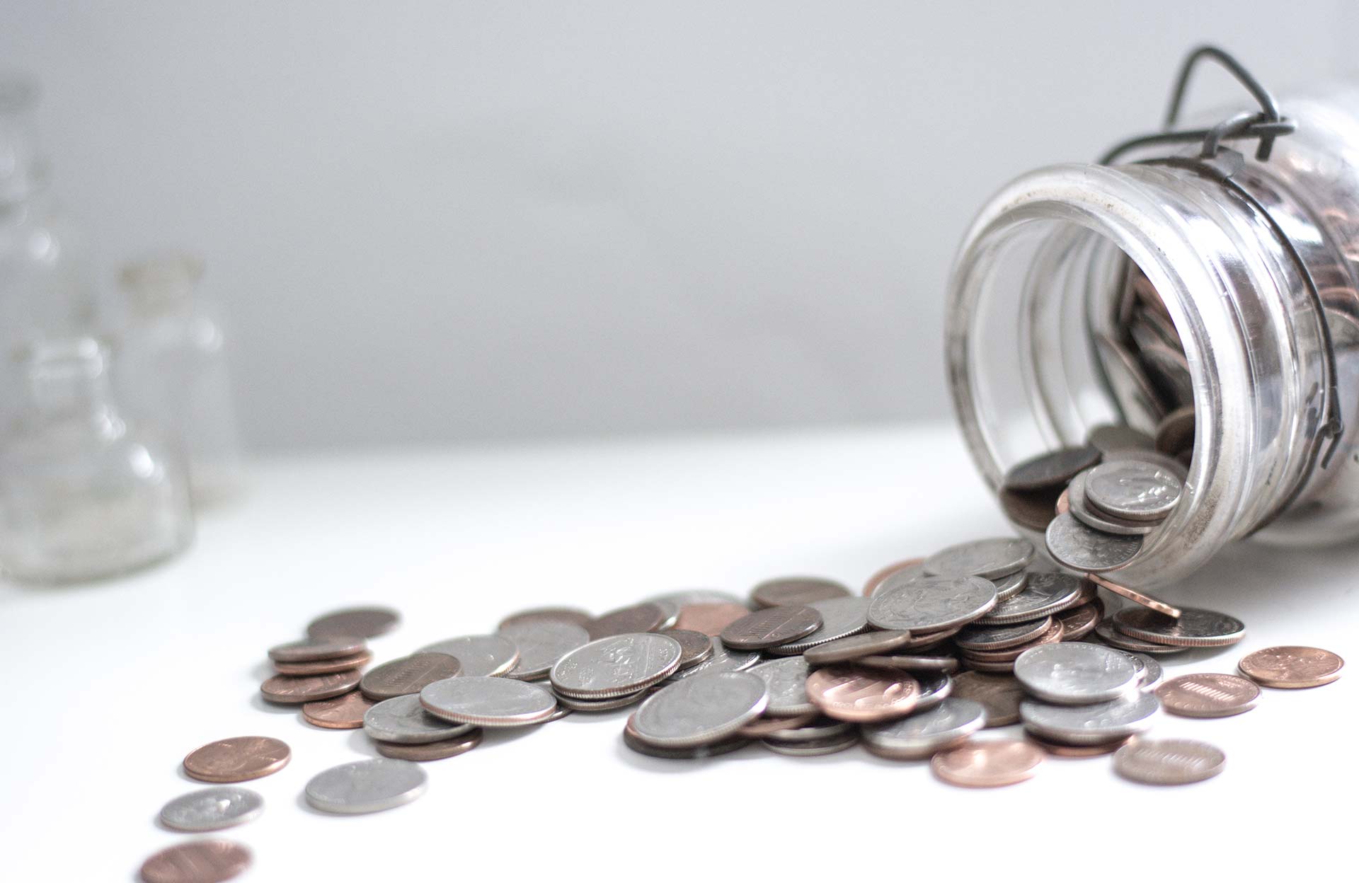 Coins spilling from a glass jar.